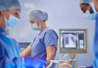 A surgical team in the operating room with an X-ray monitor in the background.&nbsp;
