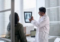 Doctor discusses chest X-ray with a woman in clinic, illustrating lung screening.