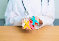 Clinician holding multicoloured cancer awareness ribbons, representing oncology care and access to treatment.&nbsp;