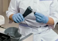 Gloved clinician disinfects a handheld medical instrument, illustrating probe reprocessing and infection control.&nbsp;
