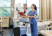 Two healthcare professionals&nbsp;reviewing&nbsp;patient data on a computer workstation in a hospital ward,&nbsp;representing&nbsp;clinical collaboration and digital record management.&nbsp;