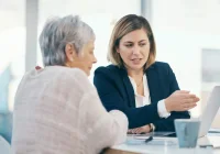 Professional consultation between an advisor and an older woman, reviewing information on a laptop.&nbsp;