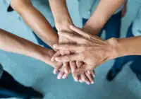 Team members joining hands to symbolise collaboration, trust and unity in a workplace setting