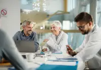 Smiling medical receptionist in scrubs speaking on phone at hospital front desk&nbsp;