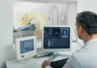 Radiologist monitoring CT scan procedure and reviewing lung images on computer screens&nbsp;