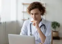 Female doctor with stethoscope working on laptop for telemedicine consultation or medical research&nbsp;