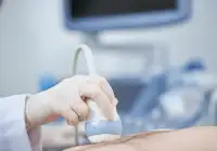 Close-up of a sonographer performing liver ultrasound on the upper abdomen in a clinical setting.&nbsp;