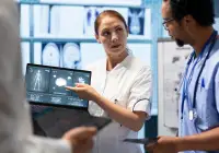 Radiology team reviewing digital imaging on a laptop during a hospital case discussion. 