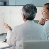 Two clinicians reviewing data on a computer screen.