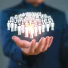 A conceptual image showing a hand presenting a digital group of people icons, symbolising population health, workforce management or community-centred healthcare.