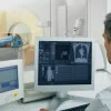 Radiologist monitoring imaging acquisition during a CT examination, illustrating real-time image review, workflow coordination and integration of diagnostic imaging systems in clinical practice.