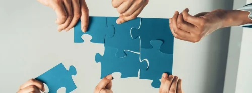 Business team collaborating to assemble puzzle pieces, symbolising teamwork and strategic collaboration. 