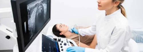 Female patient undergoing an abdominal ultrasound examination performed by a clinician using a modern ultrasound system to assess internal organs. 
