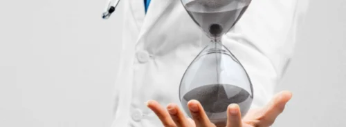 Doctor holding an hourglass symbolising time-critical decision making in medical care.