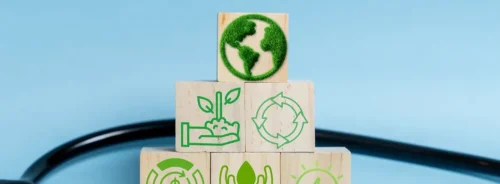 Sustainable healthcare concept illustrated with eco-icons on wooden blocks, highlighting environmental responsibility, circular economy principles and resource efficiency in health systems.