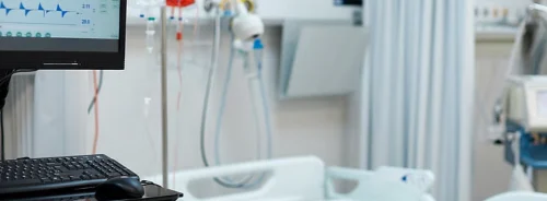 Hospital COVID ward with a medical ventilator's monitor.