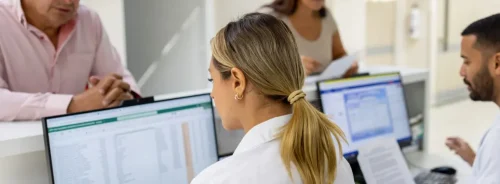 Hospital staff manage patient administration at a busy reception desk.