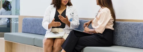 Doctor consulting with a patient in a clinic waiting area, representing outpatient care and patient communication.