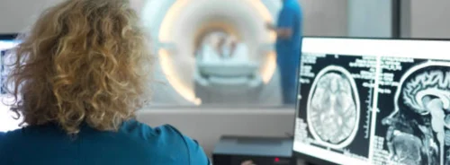 Radiology technician monitoring brain MRI imaging.
