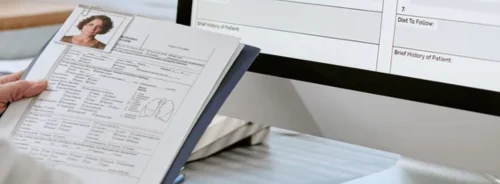 Doctor digitising patient records from paper forms, supporting electronic health records, clinical documentation and healthcare data management.