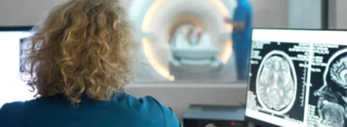 Radiographer monitoring a brain MRI scan, supporting neurological imaging, diagnostic assessment and advanced patient care.