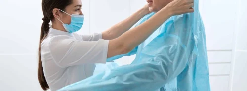 Healthcare staff handling protective gown, supporting infection control, clinical hygiene, reusable textiles and hospital safety workflows.