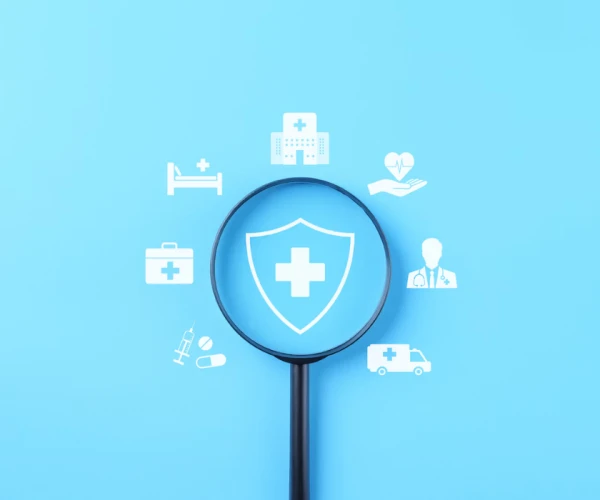 Magnifying glass highlighting a medical shield icon, symbolising healthcare protection, patient safety and system-wide health security.