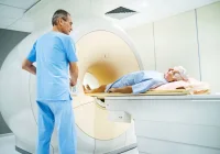 Technician preparing senior patient for MRI scan in modern radiology department 