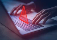 Cybersecurity warning on laptop screen with user typing, highlighting data breach risk, system vulnerability and the importance of online threat protection. 