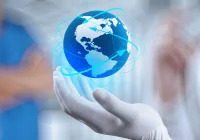 Gloved hand holding digital globe with orbit lines, symbolising global healthcare innovation, medical technology connectivity and international health collaboration. 