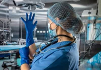 Surgeon preparing for operation by putting on sterile gloves in a modern operating theatre 