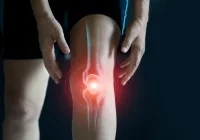 Person holding their knee with a highlighted illustration of joint pain or inflammation, symbolising arthritis or musculoskeletal discomfort. 