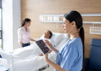 Nurse using digital tablet to monitor patient vitals.