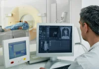 Radiologist monitoring imaging acquisition during a CT examination, illustrating real-time image review, workflow coordination and integration of diagnostic imaging systems in clinical practice.