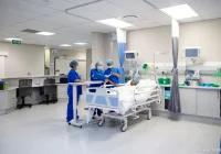 Clinical team reviewing patient status at the bedside in a modern hospital ward, illustrating coordinated care, monitoring, and multidisciplinary decision-making.