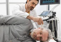 Clinician performing a carotid ultrasound scan, supporting vascular assessment, stroke risk evaluation and diagnostic imaging.