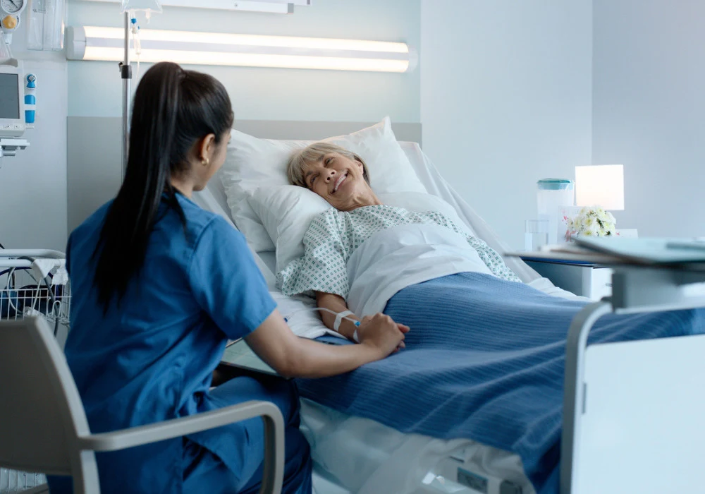 Elderly woman receiving care in hospital – nurse providing comfort and reassurance during recovery 