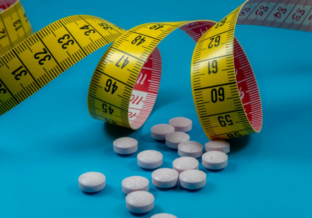 Weight loss concept with pills and measuring tape symbolising diet supplements and obesity treatment 
