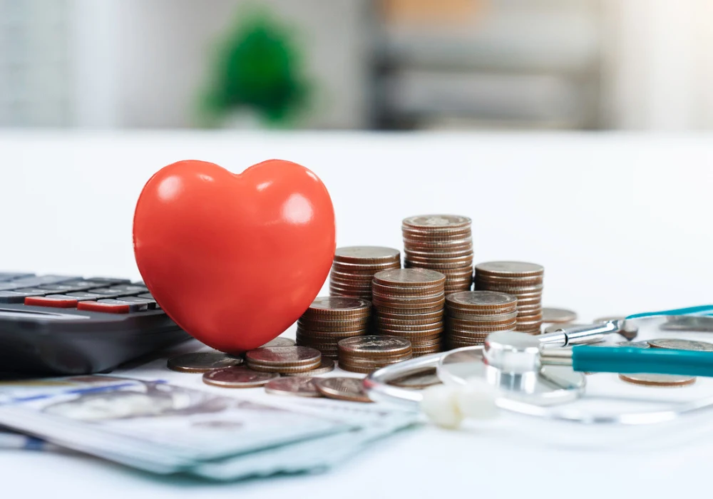 Healthcare costs and financial planning concept with heart model, coins, stethoscope and calculator. 