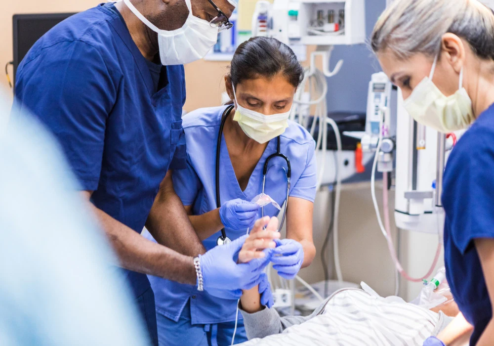 Medical team in protective masks treating patient in intensive care unit during emergency procedure. 