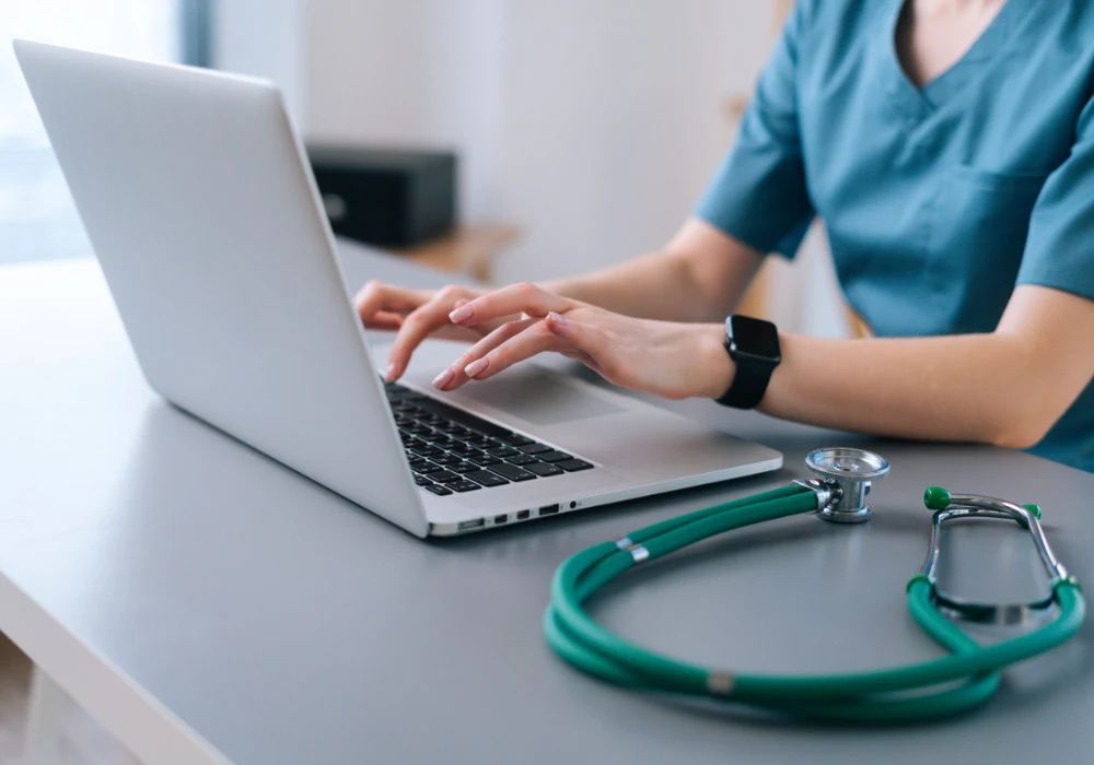 Healthcare professional using laptop for digital patient records and telemedicine support 