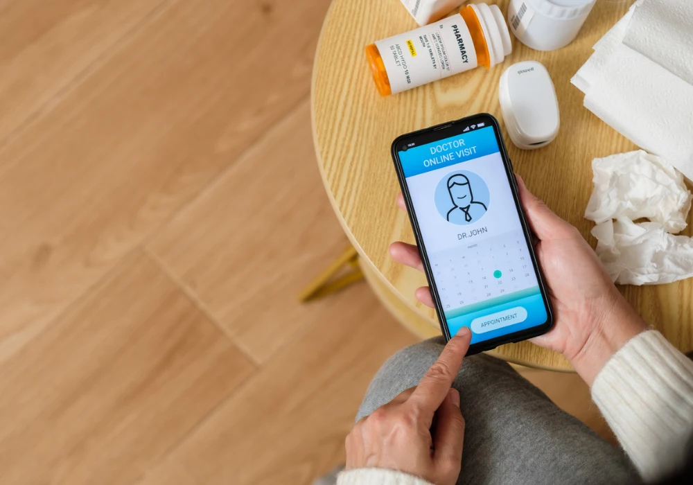 Patient using telemedicine app on smartphone to schedule online doctor appointment with prescriptions nearby 