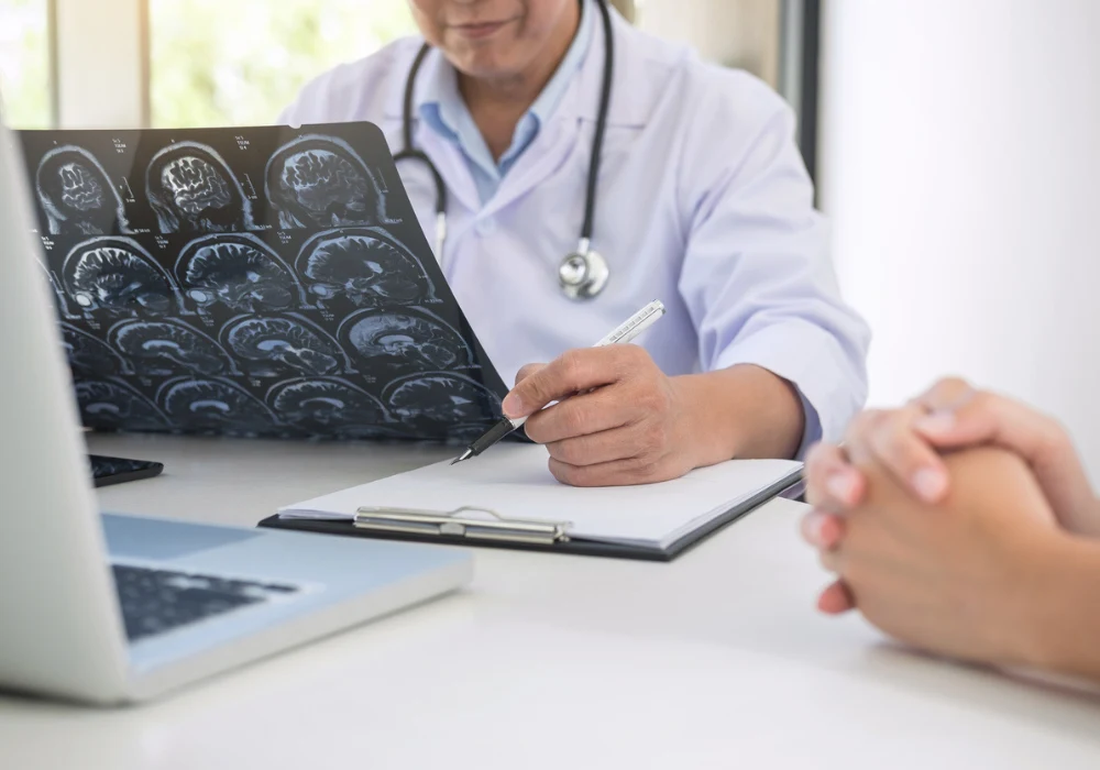 Doctor reviewing brain MRI scans and taking notes during patient consultation. 