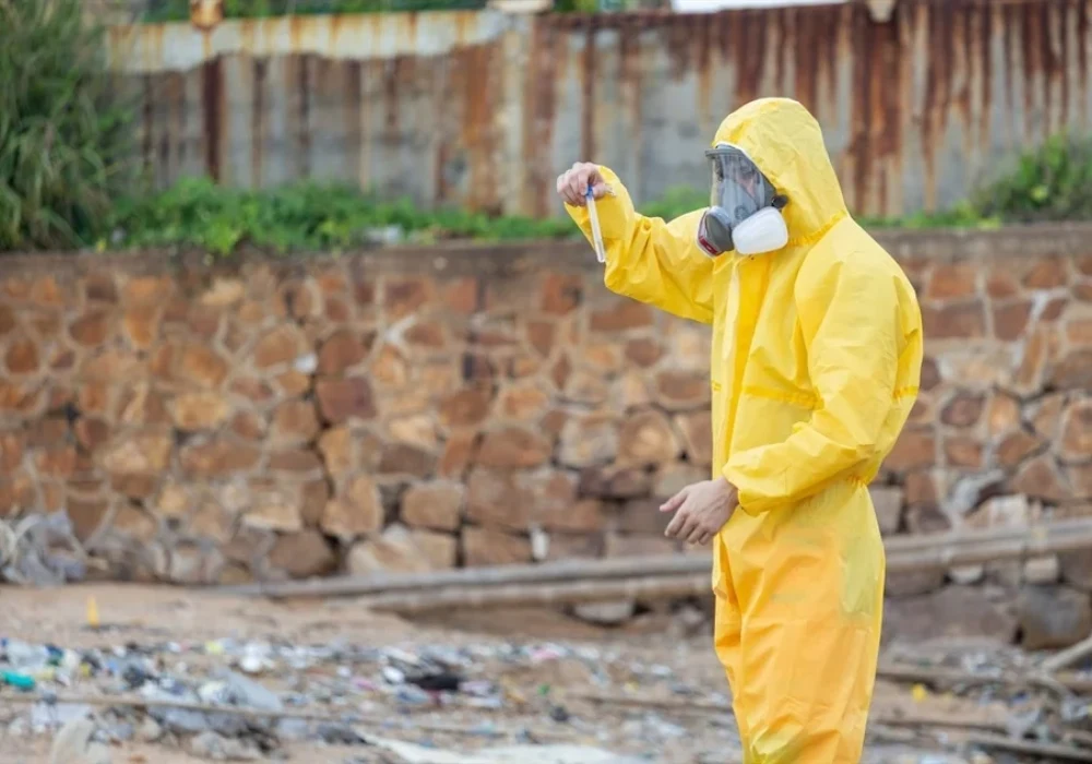 Field researcher collecting environmental samples near a waterway, illustrating wastewater surveillance and public health monitoring for early detection of health risks.