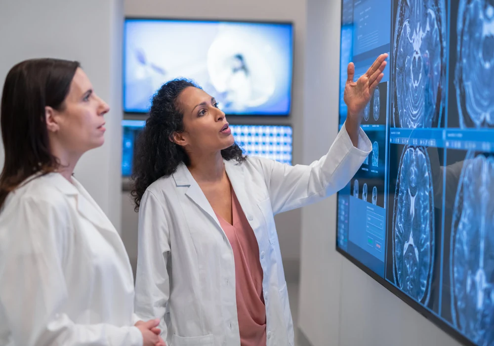 Medical specialists reviewing brain imaging scans on a digital display in a radiology department.