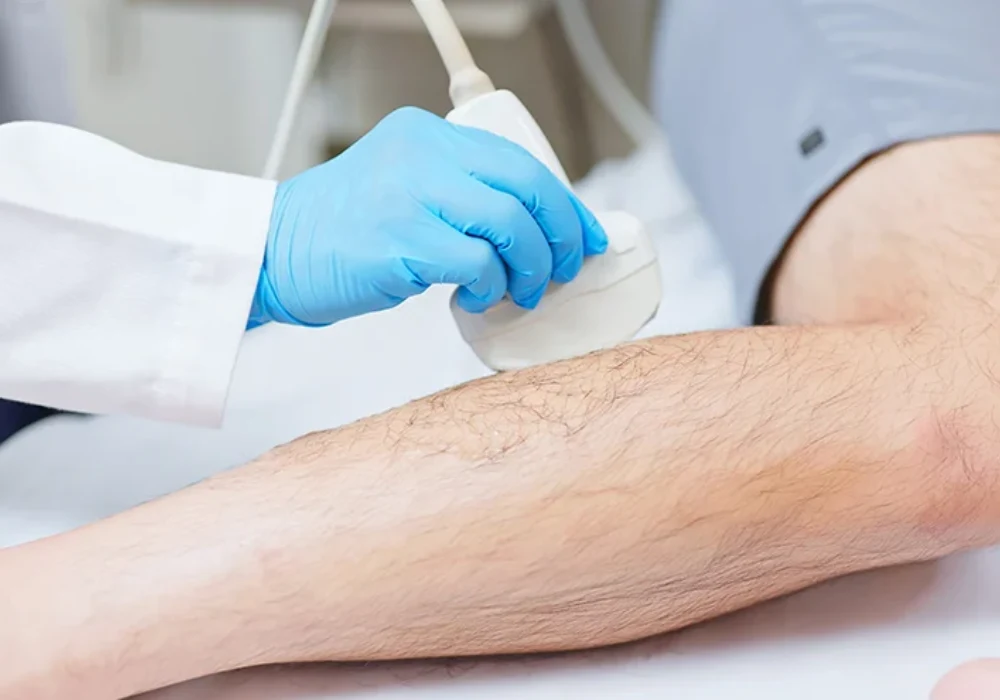 Ultrasound examination of the lower limb, showing a clinician using a handheld probe to assess soft tissue and vascular structures in a clinical setting.