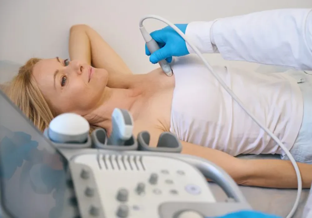 Clinician performing diagnostic ultrasound examination while reviewing real-time imaging on screen.