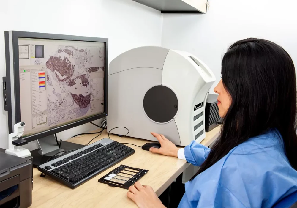 Laboratory specialist analysing digital pathology images at a workstation.