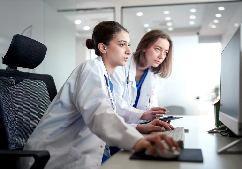 Two clinicians reviewing medical data together on a desktop computer.