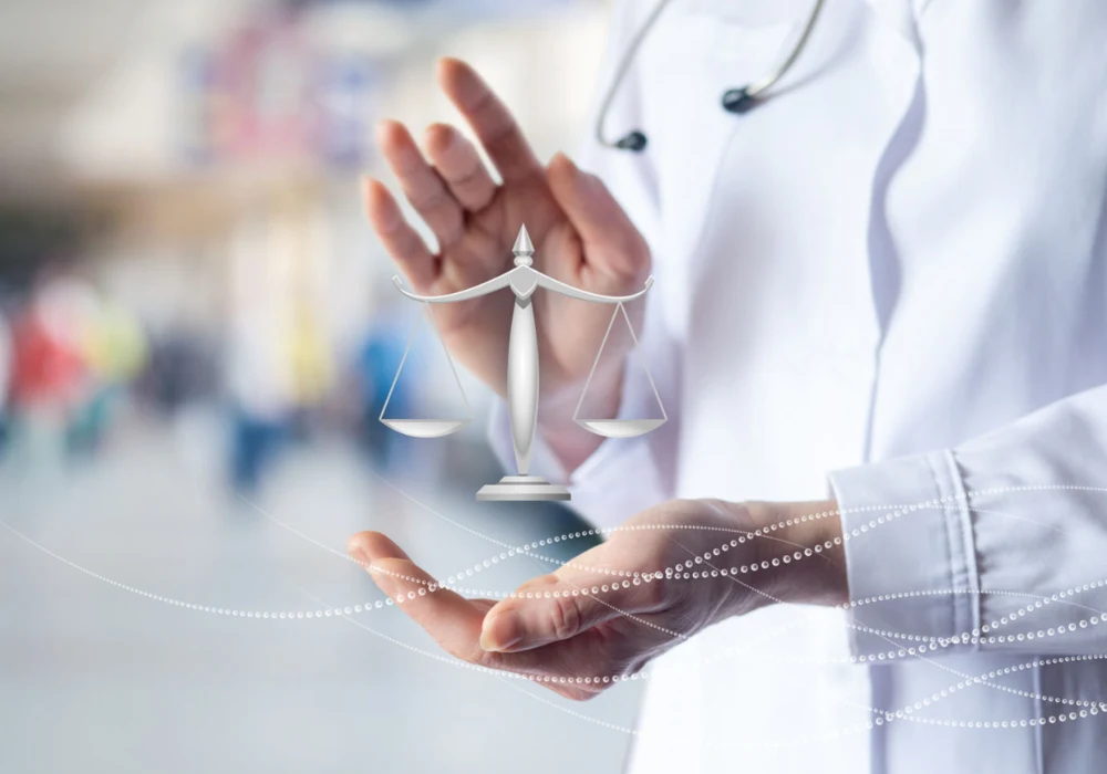 Healthcare professional holding justice scale symbolising medical ethics, compliance and patient rights protection.